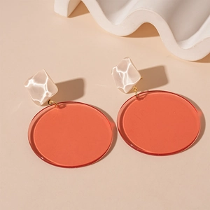 Detailed shot of resin geometric earrings with white pearl texture and amber circles