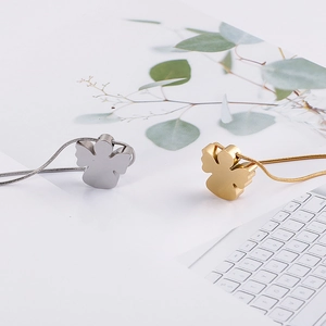 Detail view of gold and silver angel pendant necklaces on a minimalist desktop background