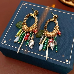 Detail of bohemian leaf and feather tassel earrings with colorful beads on a star pattern box