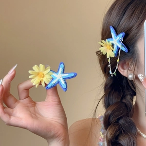 Floral raffia starfish hair clip with yellow daisy and blue sea star on a model