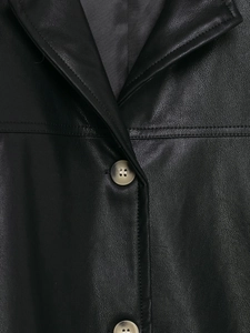 Close-up of black leather jacket collar featuring textured beige buttons and stitching