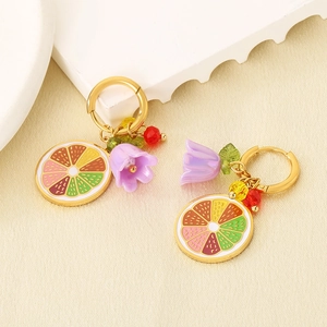 Detailed view of stainless steel lemon slice and purple flower charms on gold hoop earrings