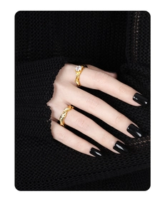 Close-up of dual gold rings with irregular texture and sparkling zircons on black fabric