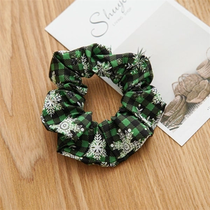 Detail of Christmas green and black buffalo plaid scrunchie with white snowflake patterns