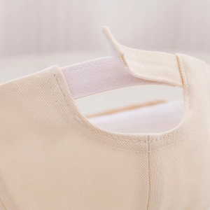 Dettaglio ravvicinato del cappellino beige per neonati con cinturino in velcro
