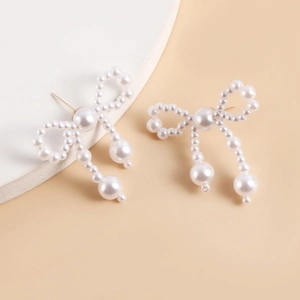 Detailed view of handmade pearl bow drop earrings featuring elegant gold metal posts