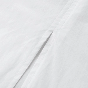 Detail of side slit and high-quality stitching on white cotton maxi dress fabric