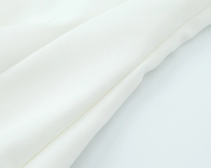 Macro shot of white textile fabric showing diagonal fine twill texture and drape