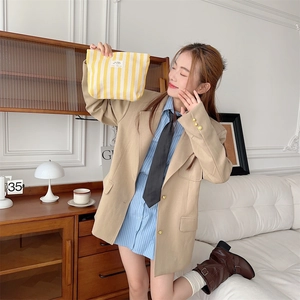 Detail of yellow and white striped toiletry bag held by model in professional studio setting