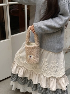 Detail of soft cream plush bucket bag with teddy fleece texture and woven label