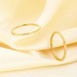 Nahaufnahme der mattgoldenen Oberfläche eines dünnen Edelstahlrings im Minimal-Design.