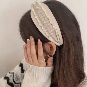 Detail of beige tweed headband with small pearl trim and large central pearls on hair