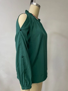 Detail of dark green cold-shoulder top with ruffle neck and pearl sleeve accents
