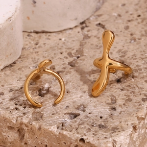Macro detail of 18K gold plated fluid melt rings on textured stone surface