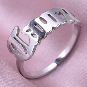Macro detail of the silver stainless steel open ring with BABY cutout design on pink silk
