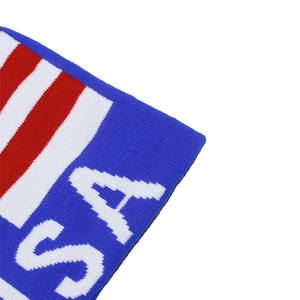 Detail of knitted USA beanie showing blue fabric with white letters and red striped texture