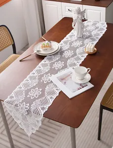 Detail of white vintage lace table runner with hollow floral pattern and fringe