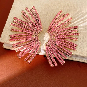 Macro detail of fan-shaped earrings with pink rhinestones on a gold metal base
