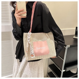 Détail d'un sac cabas en paille d'été avec poche en cuir rose et décoration en foulard