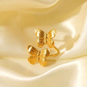 Macro shot of gold double butterfly open ring with textured wings on champagne silk