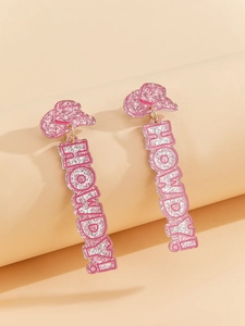 Detail of pink glittery cowboy hat earrings with vertical Howdy letters on a beige background