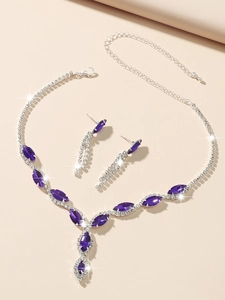 Detailed view of silver necklace and earrings set with purple marquise gems and rhinestones