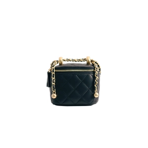 Detail of black quilted leather vanity bag with gold-tone chain strap and top handle