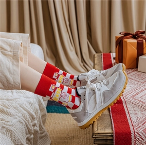 Detail of red and white plaid Christmas socks with lucky characters paired with sneakers