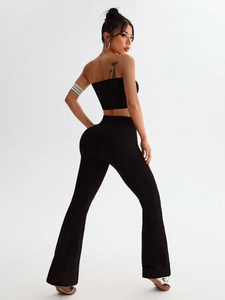 Detail shot of black seamless high-waist yoga flared pants and crop top on model
