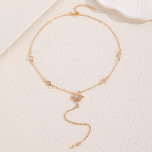 Détail d'un collier doré avec pendentif soleil serti de cristaux sur fond texturé
