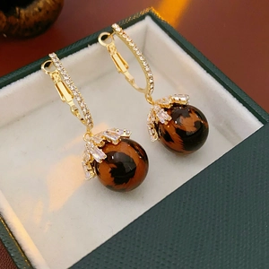 Detail of leopard print ball earrings with gold leaf-shaped crystal accents in a jewelry box