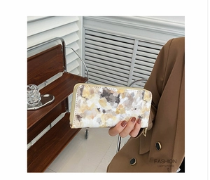 Detail of a marble pattern long wallet for women with golden zipper in hand