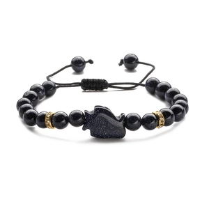 Dettaglio macro del bracciale con pietre blu, ciondolo a lupo e cordino intrecciato