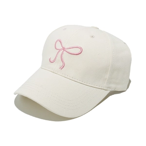 Close-up of pink ribbon embroidery on a cream cotton canvas baseball cap for women