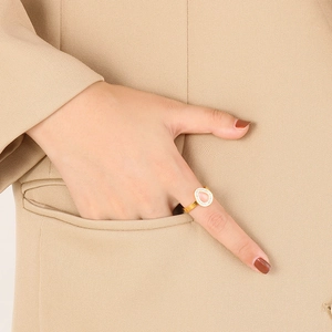 Detail of a gold pear-cut pink gemstone ring with diamond halo on a model's hand
