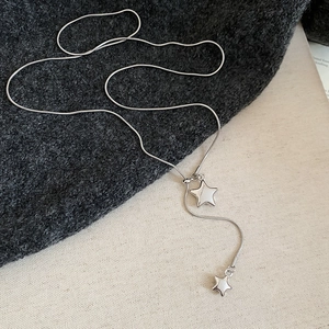 Detailed shot of silver star pendant necklace with Y-shape tassel on knit fabric texture