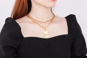 Detail of double-layer gold necklace featuring a rectangular pendant with hollow hearts