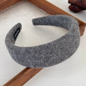 Close-up of grey wool felt headband with a handmade label on wooden tray