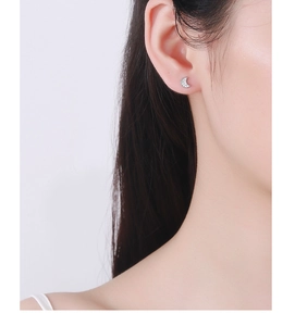 Close-up of 925 silver crescent moon earring with zircon inlay worn on an ear
