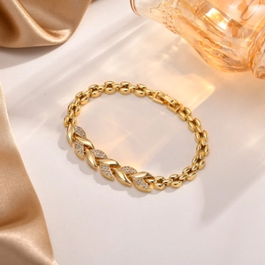 Elegantes vergoldetes Kupferarmband in Blattform mit Zirkonia auf seidenem Hintergrund