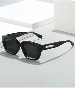 Detail of square black sunglasses with golden metal accents on a geometric display