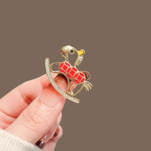 Macro shot of rocking horse brooch with red enamel and pavé rhinestones on gold base
