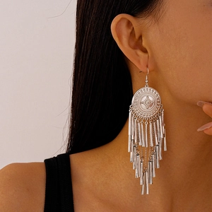 Close-up of silver bohemian drop earrings featuring geometric patterns and metal tassels