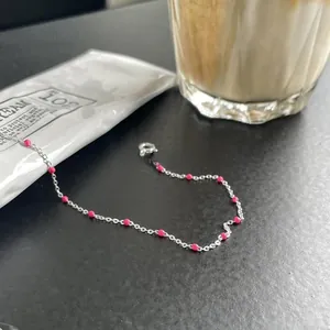 Macro shot of fine 925 sterling silver chain with vibrant pink bead details on black surface