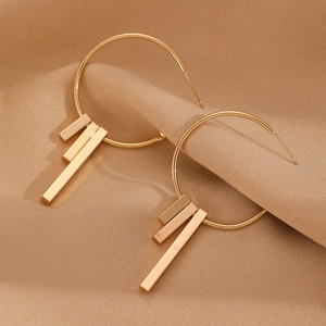 Detail view of gold geometric hoop earrings with tiered long bar pendants on silk