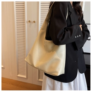 Lifestyle view showing the capacity and drape of the cream lychee grain leather tote bag