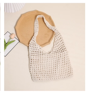 Top view of cream hollow knit cotton tote bag with wooden tray and white flowers