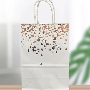 White kraft paper gift bag with metallic rose gold heart pattern and rope handles