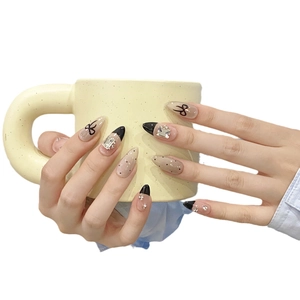 Handmade almond press-on nails with black French tips, bows, and sparkling rhinestones
