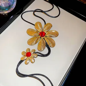 Golden flower pendant tassel necklace with red crystals and elegant black cord